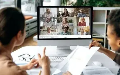 Twee medewerkers voeren via WeSeeDo een videogesprek met zes andere deelnemers.